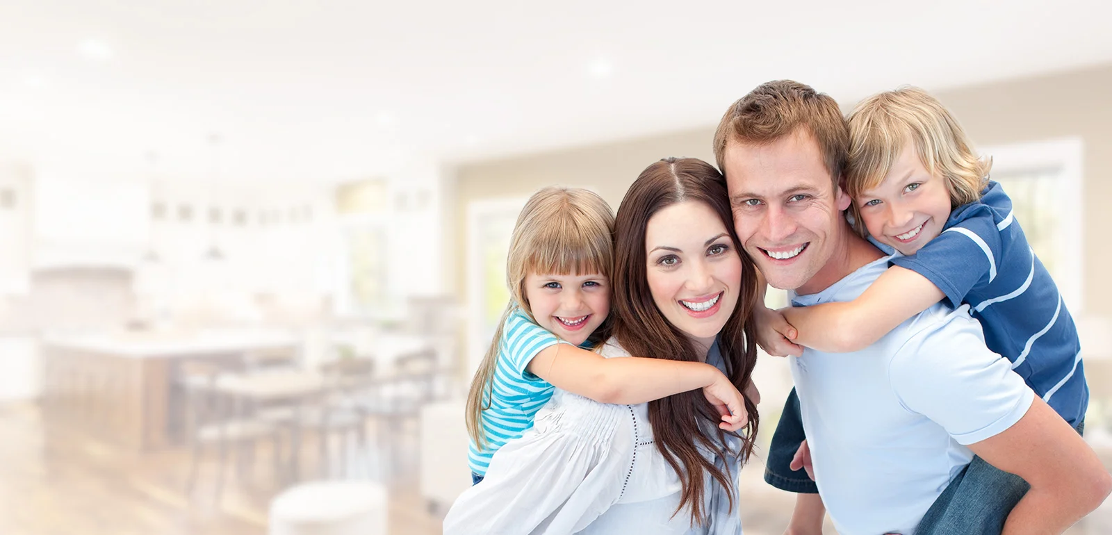 Happy family of four smiling together in bright, modern home interior.